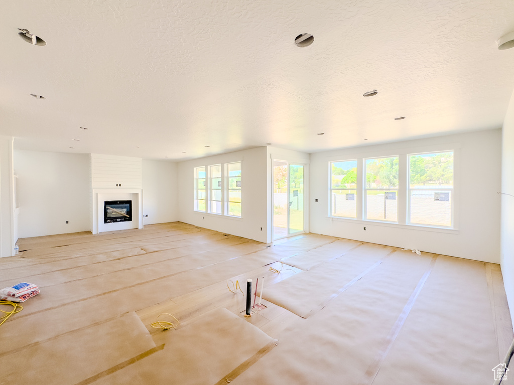 Unfurnished living room featuring a large fireplace and a textured ceiling