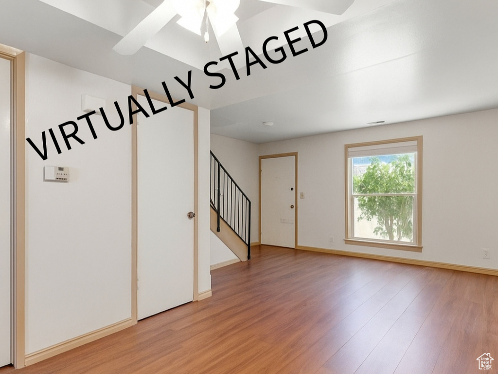 Empty room with light wood finished floors, stairway, and ceiling fan