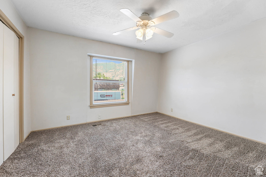 Unfurnished bedroom featuring carpet, a closet, a ceiling fan, and a textured ceiling