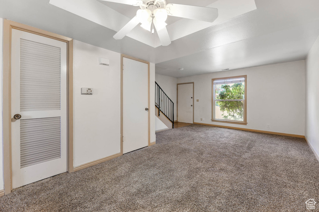 Carpeted spare room with stairs and ceiling fan