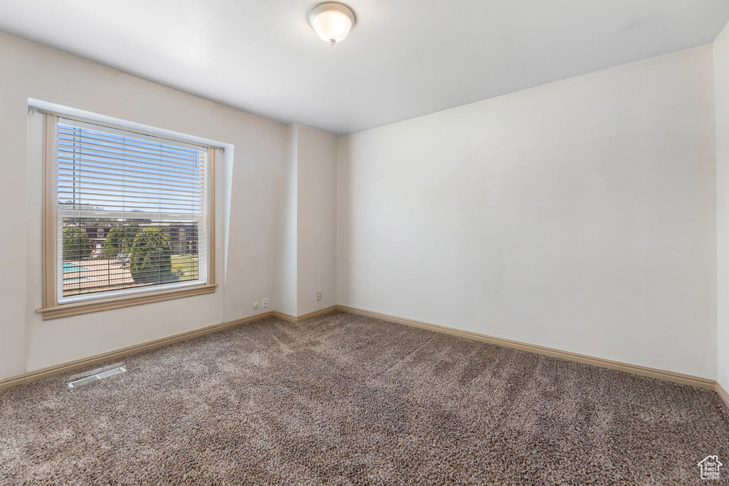 Carpeted spare room featuring baseboards