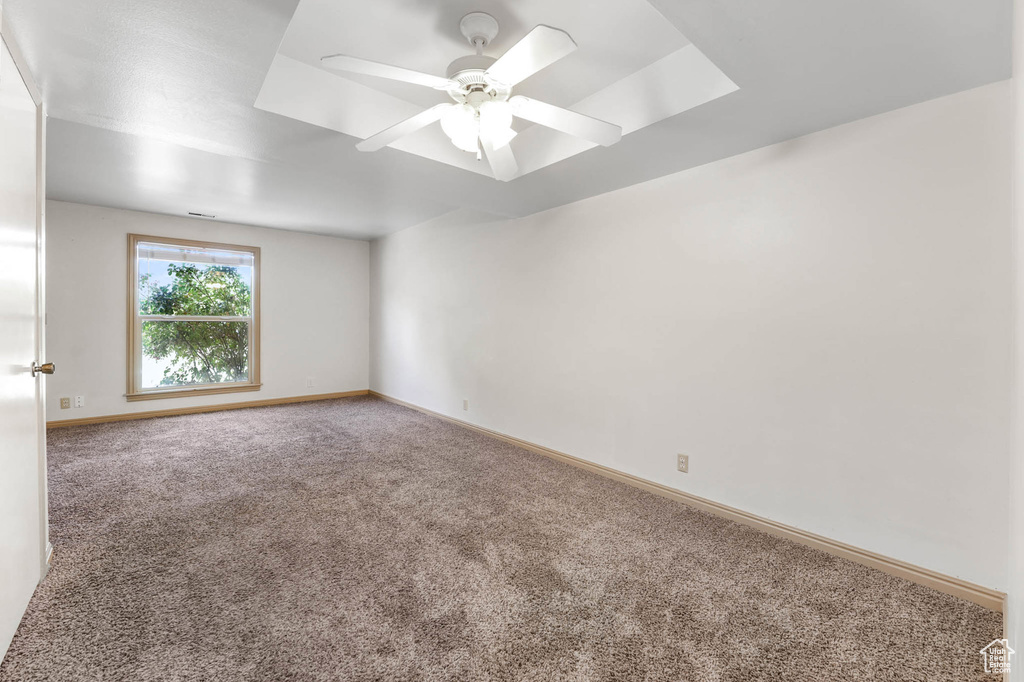 Carpeted spare room featuring baseboards and a ceiling fan