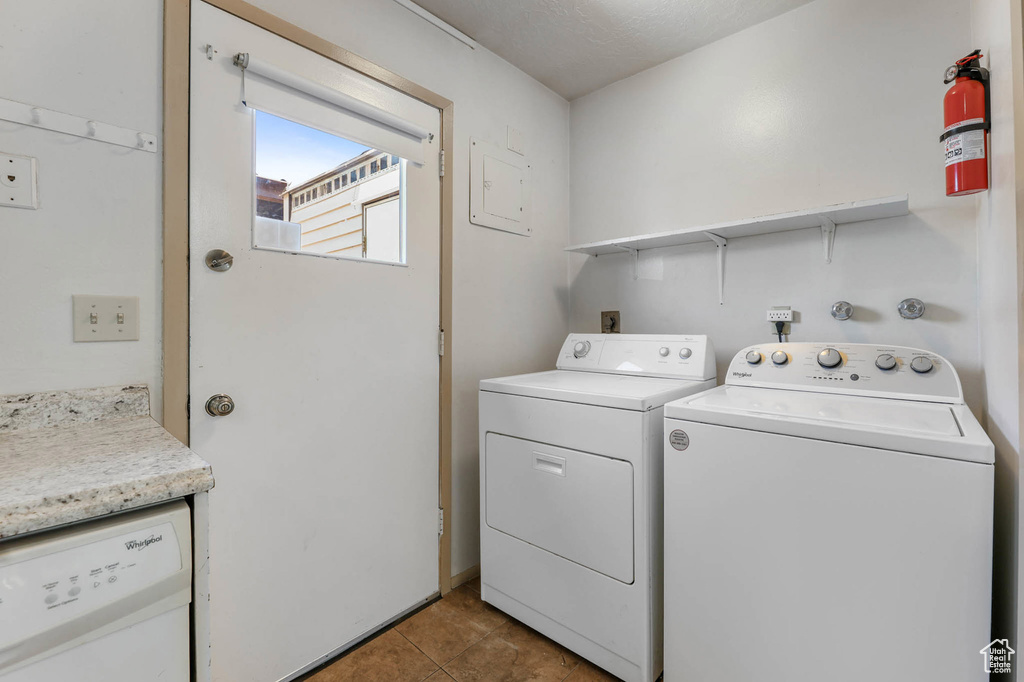 Washroom with tile patterned floors, washer and clothes dryer, and electric panel