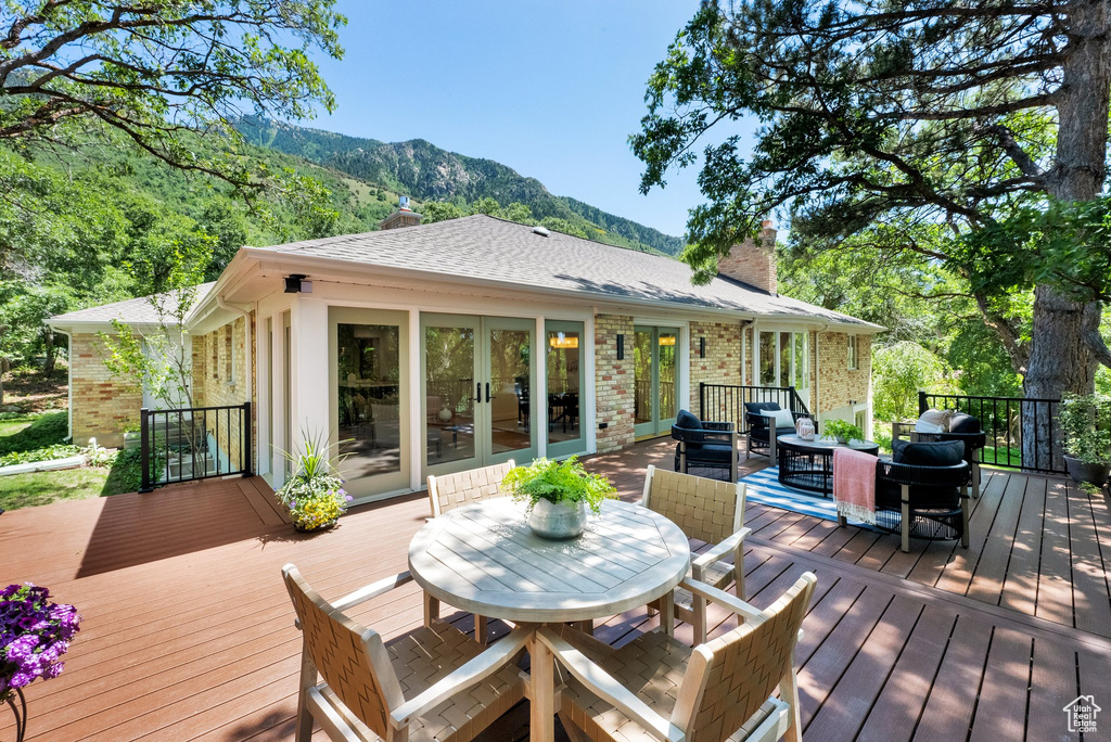 Wooden deck with french doors, a mountain view, outdoor dining space, and outdoor lounge area