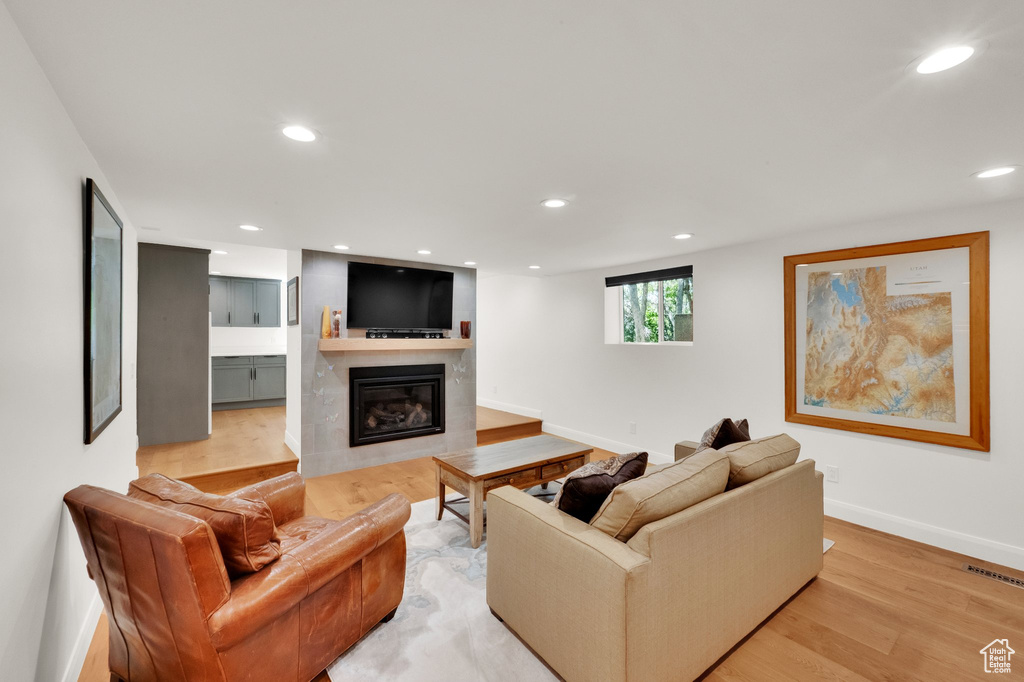 Living room featuring a large fireplace, light wood-style flooring, and recessed lighting
