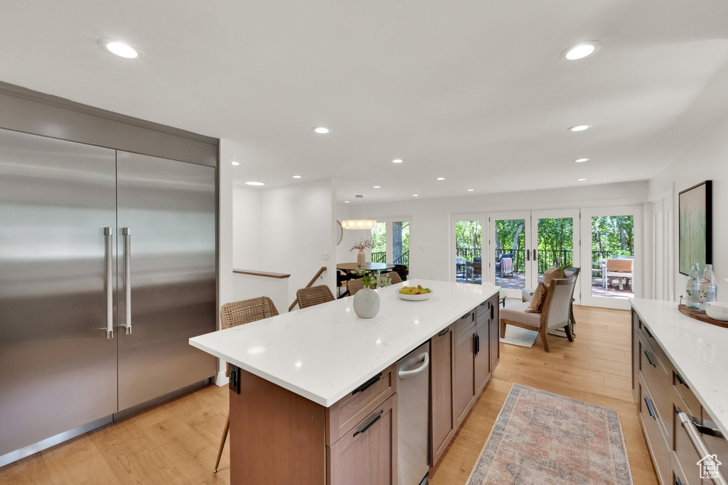 Kitchen with stainless steel built in fridge, recessed lighting, light wood finished floors, a breakfast bar, and light countertops