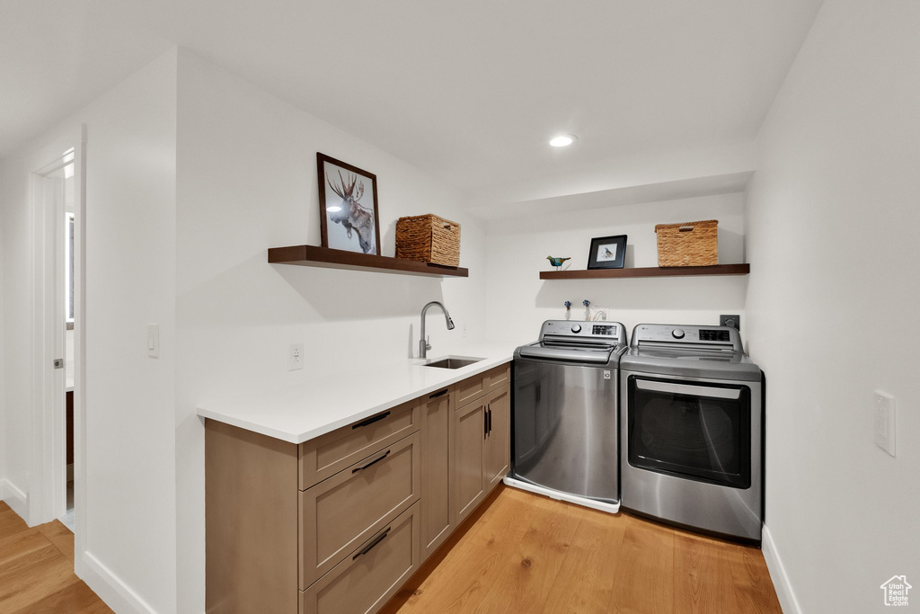 Washroom with independent washer and dryer, cabinet space, light wood finished floors, and recessed lighting