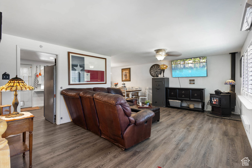 Living area featuring a wood stove, wood finished floors, and a ceiling fan