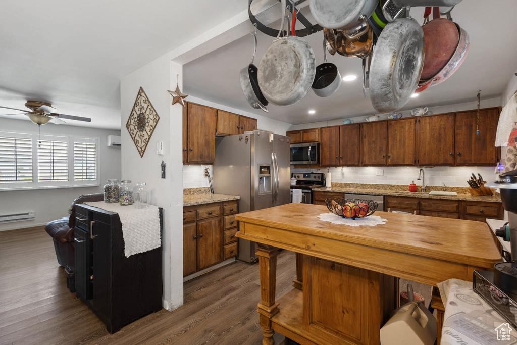 Kitchen with appliances with stainless steel finishes, dark wood finished floors, a ceiling fan, and brown cabinetry