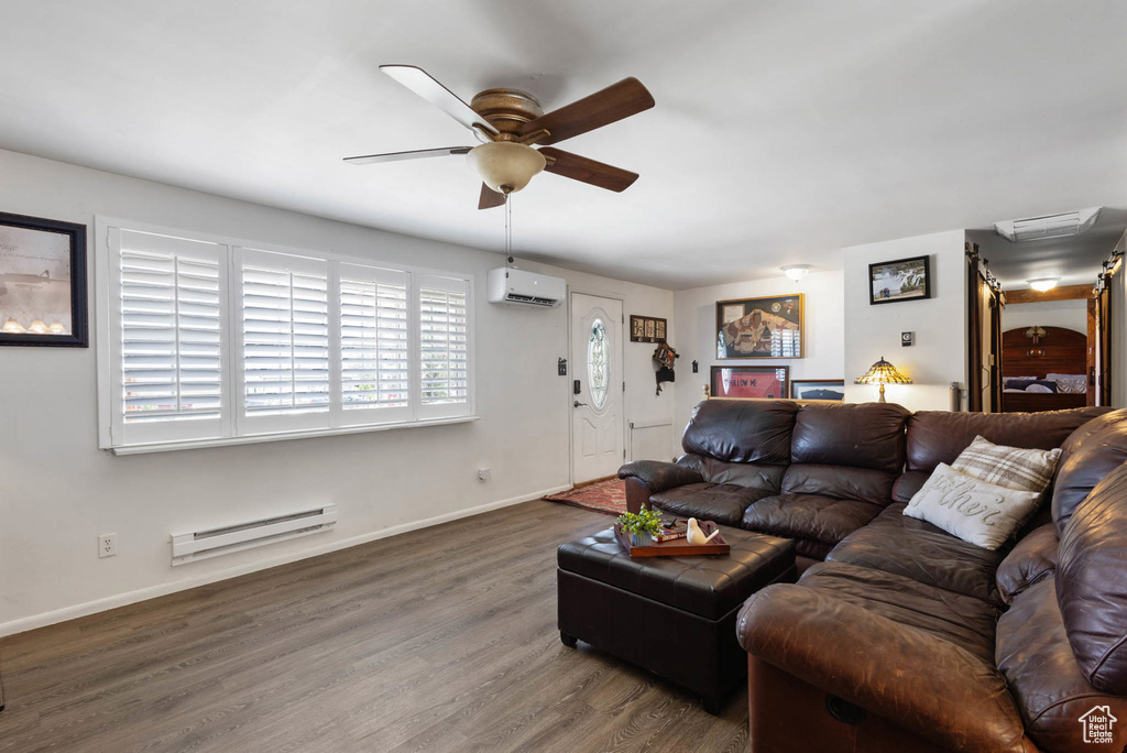 Living room featuring an AC wall unit, a baseboard heating unit, a ceiling fan, and wood finished floors