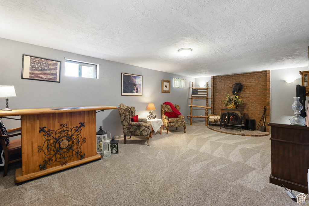 Living area featuring carpet flooring, a wood stove, and a textured ceiling