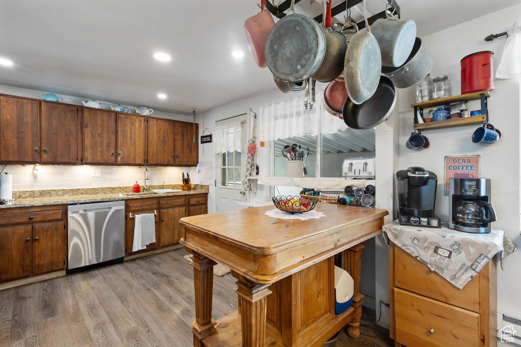 Kitchen featuring stainless steel dishwasher, light wood-style floors, brown cabinetry, and recessed lighting