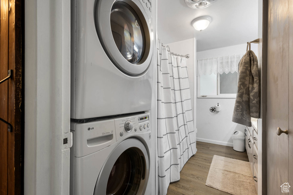 Washroom featuring stacked washing machine and dryer and wood finished floors