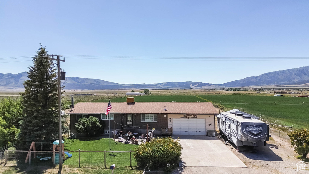 View of front of property with a mountain view, a garage, driveway, and a view of rural / pastoral area