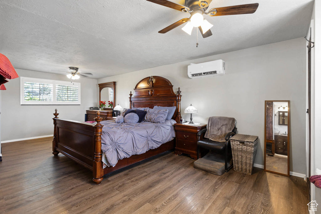 Bedroom featuring an AC wall unit, wood finished floors, ceiling fan, and a textured ceiling