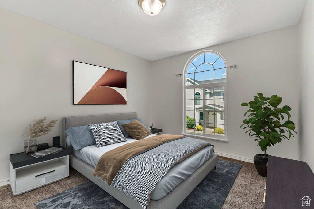 Carpeted bedroom featuring baseboards and a textured ceiling