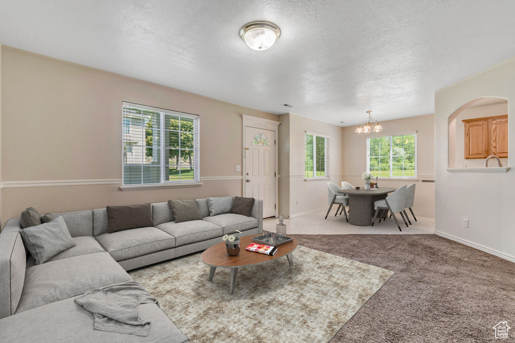 Carpeted living room with a chandelier and a textured ceiling