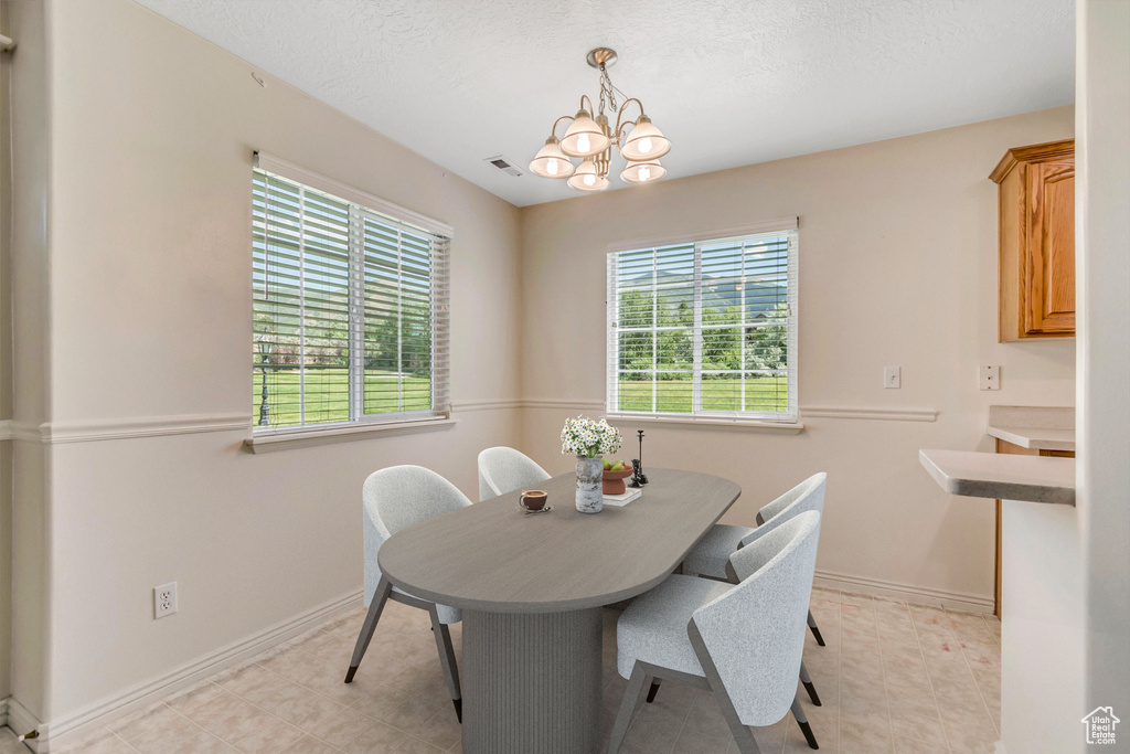 Dining area with plenty of natural light, a chandelier, and a textured ceiling