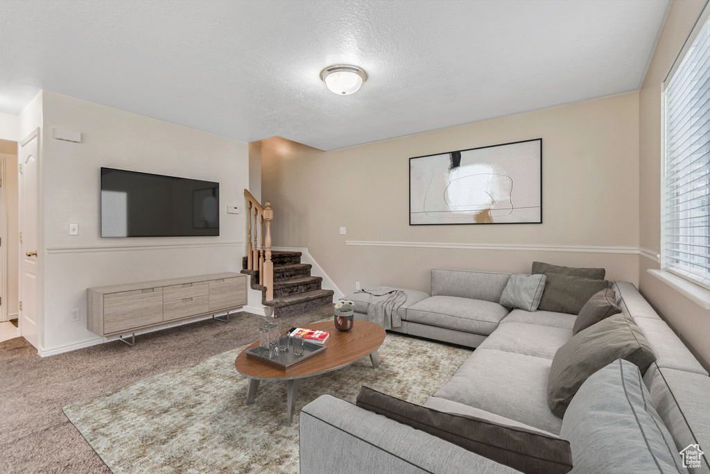 Living room featuring stairway, carpet, and a textured ceiling