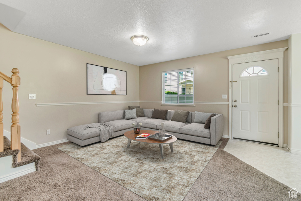 Living room featuring stairs, carpet, and a textured ceiling