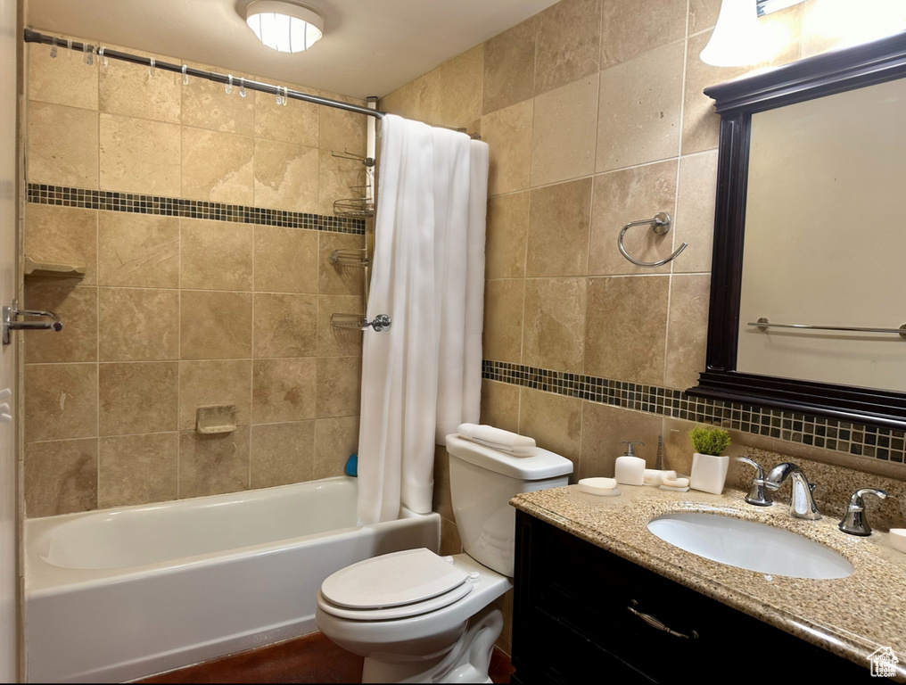 Bathroom with tile walls, shower / bath combination with curtain, vanity, and decorative backsplash