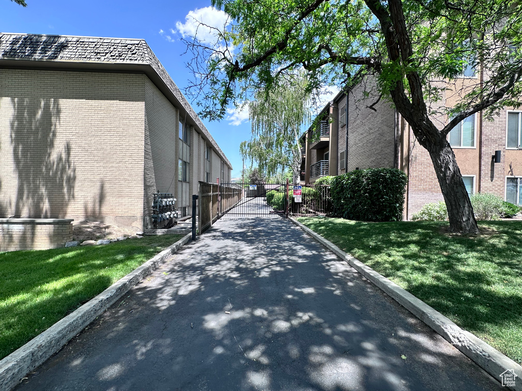 View of asphalt road featuring a gate and curbs