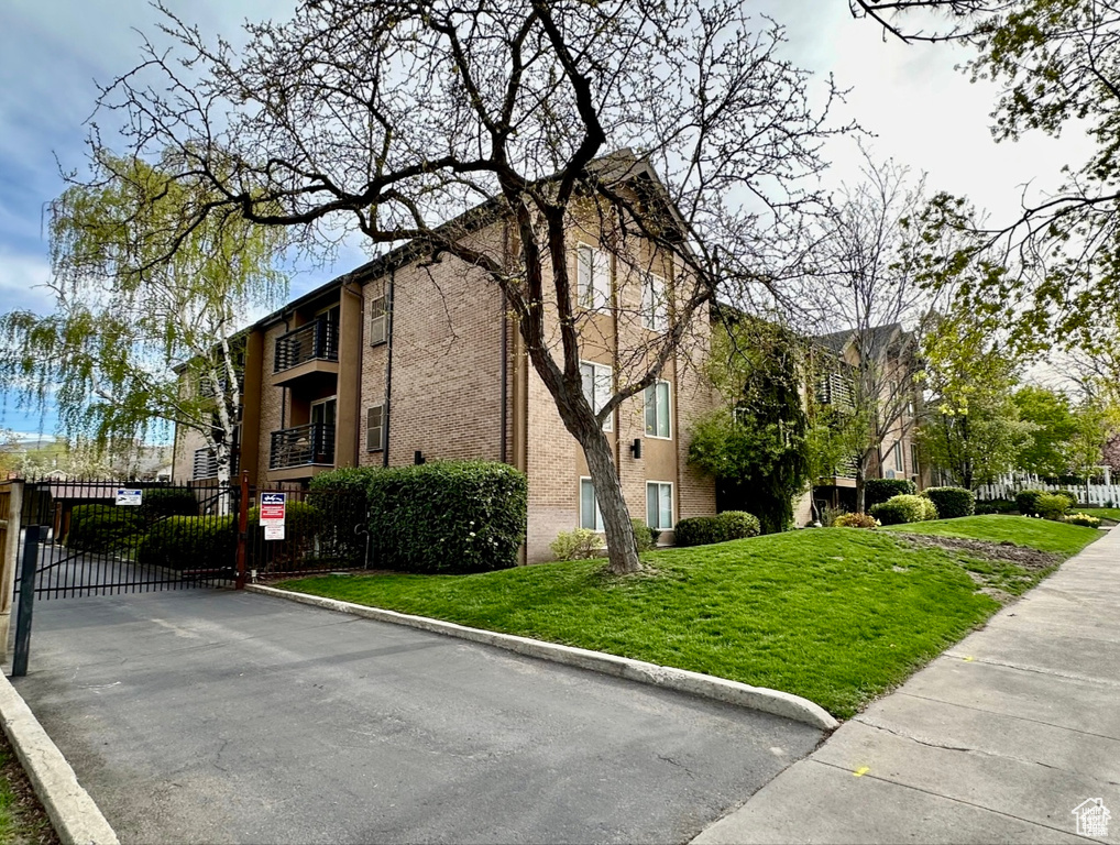 View of side of home featuring a gate and brick siding