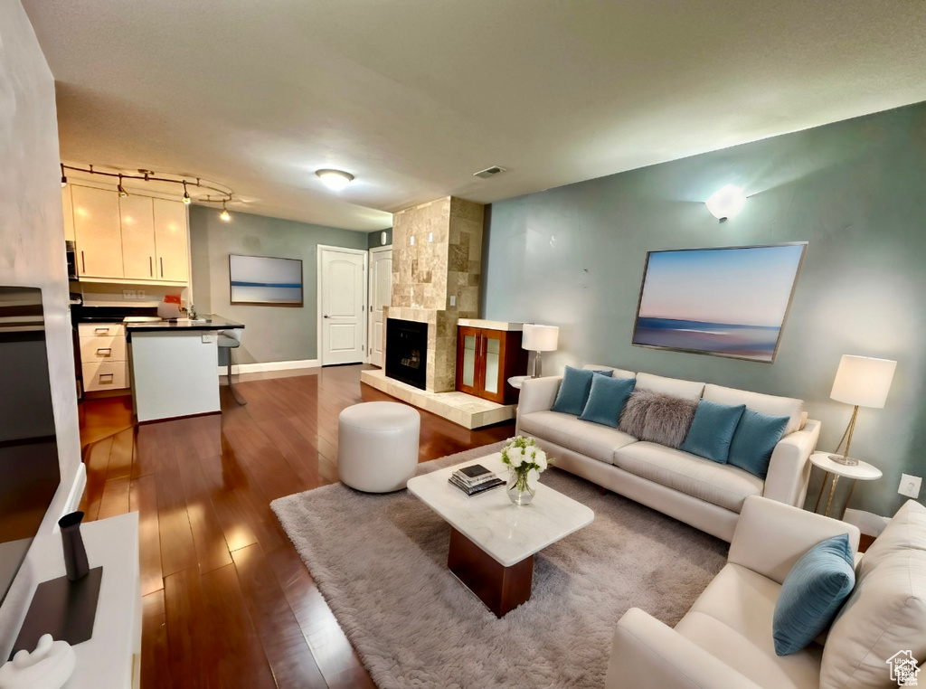 Living room with dark wood-type flooring and a large fireplace