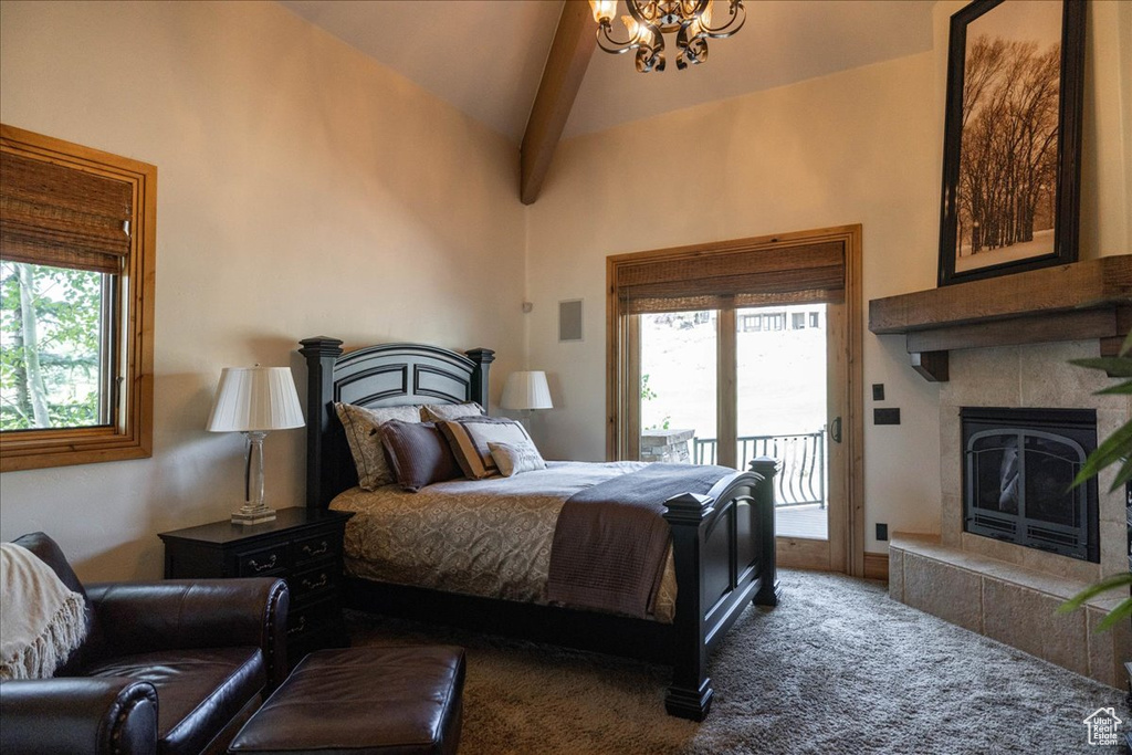 Bedroom with access to exterior, a tiled fireplace, carpet floors, a chandelier, and high vaulted ceiling