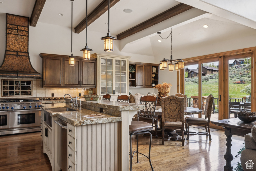 Kitchen with appliances with stainless steel finishes, a kitchen breakfast bar, open shelves, tasteful backsplash, and an island with sink