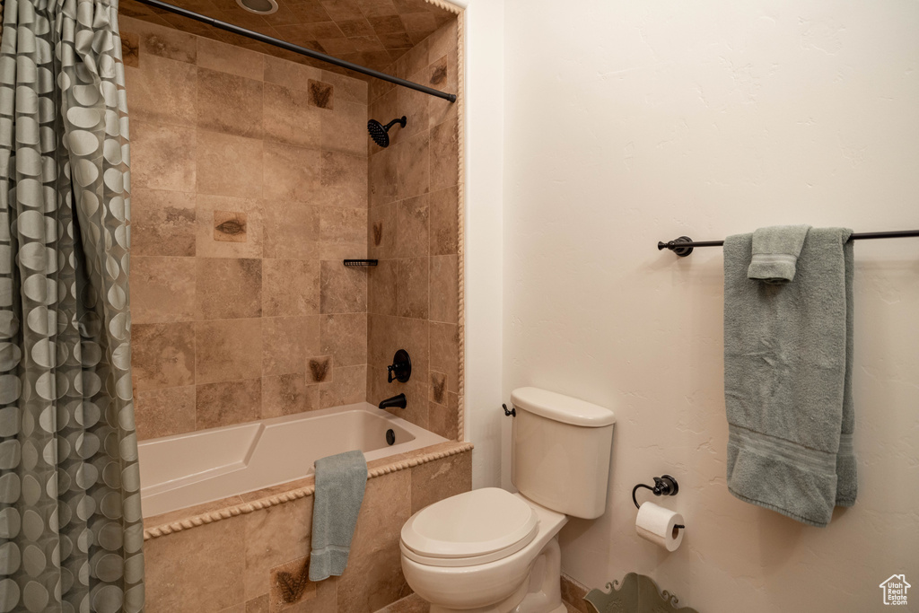 Bathroom with tiled shower / bath and toilet