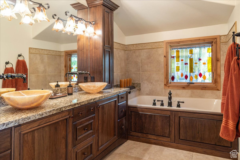 Full bathroom featuring double vanity, a garden tub, and a chandelier