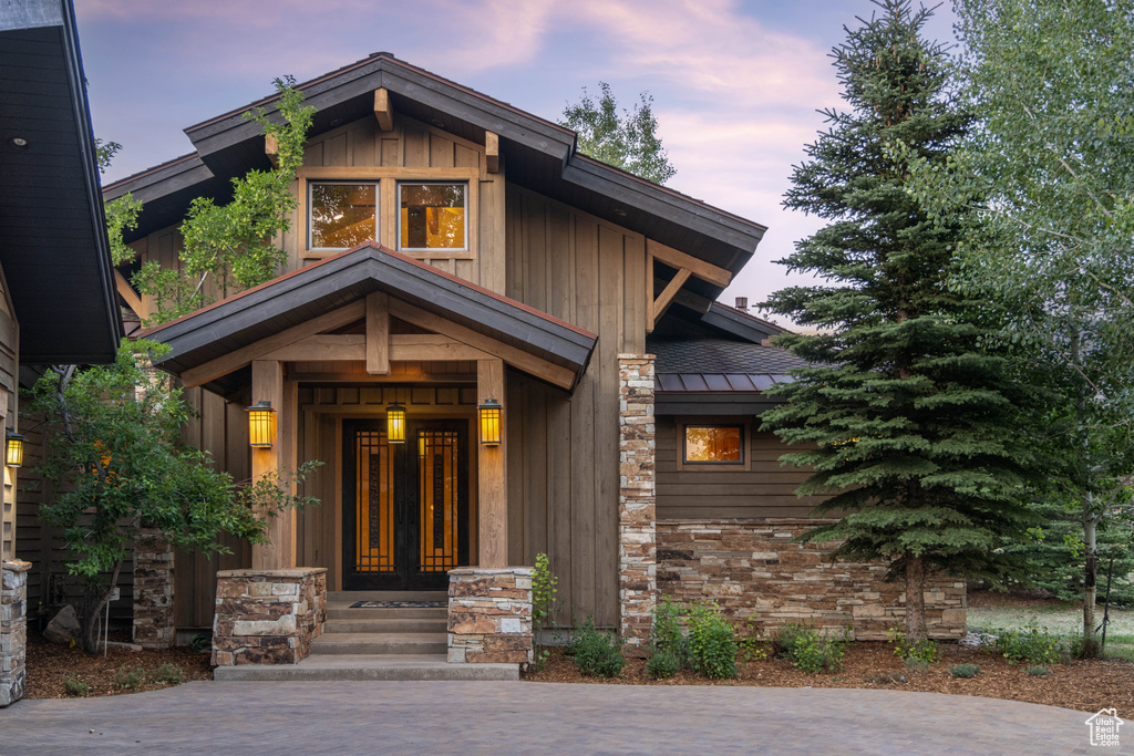 Exterior entry at dusk with a standing seam roof, a metal roof, and board and batten siding