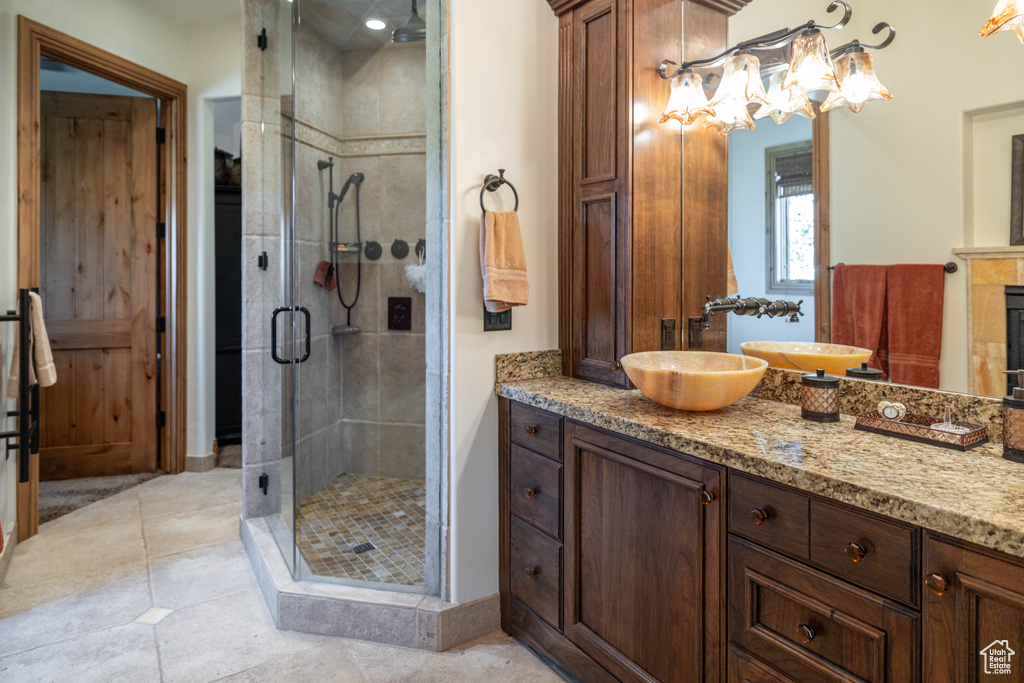Bathroom with a shower stall, vanity, tile patterned flooring, and a fireplace