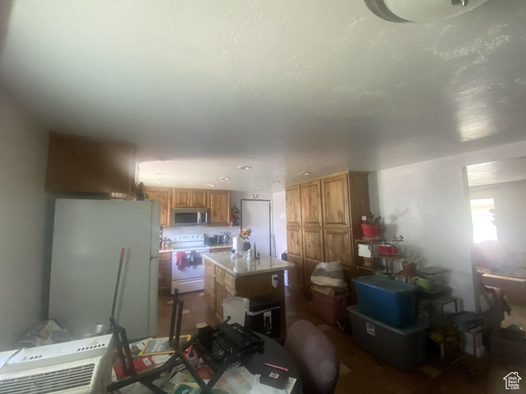 Kitchen with stainless steel microwave, electric range, fridge, light countertops, and a center island