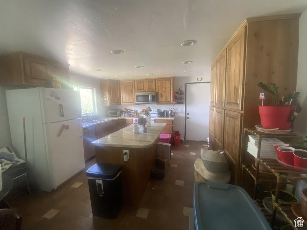 Kitchen featuring freestanding refrigerator, stainless steel microwave, a kitchen island, light countertops, and recessed lighting