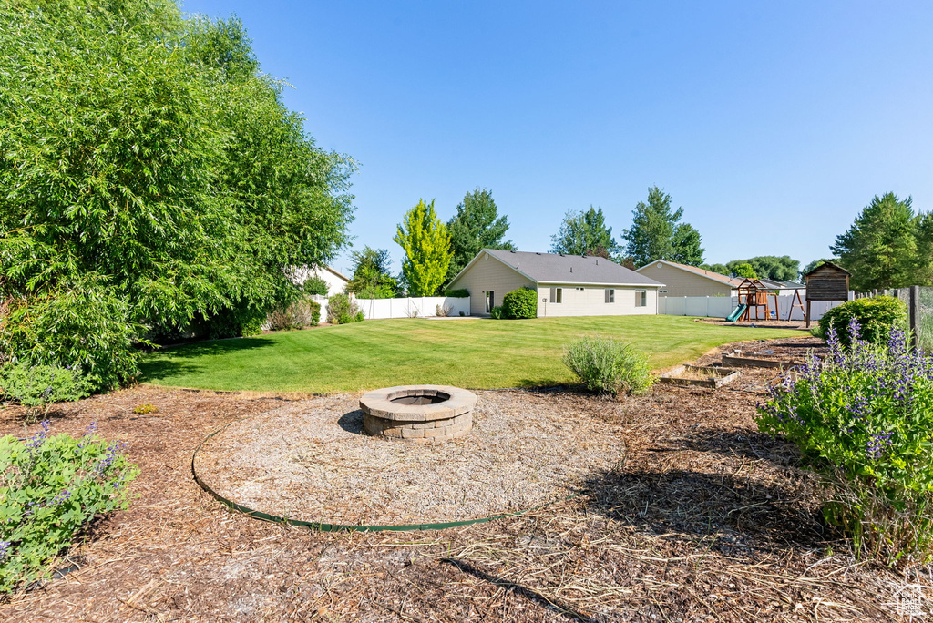 View of yard with a playground and a fire pit