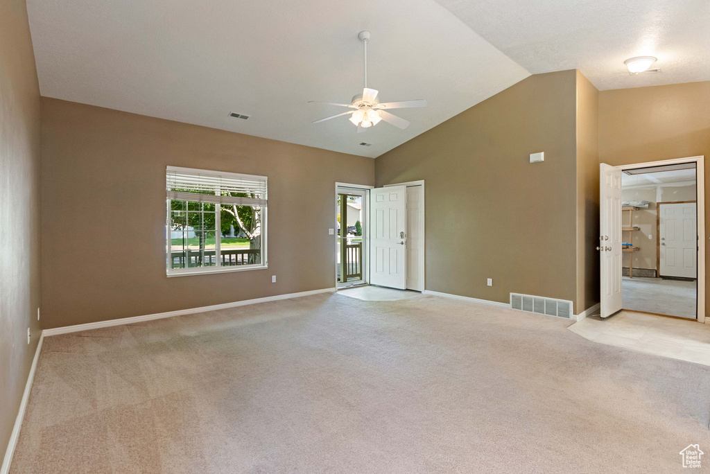 Empty room featuring ceiling fan, light colored carpet, and lofted ceiling