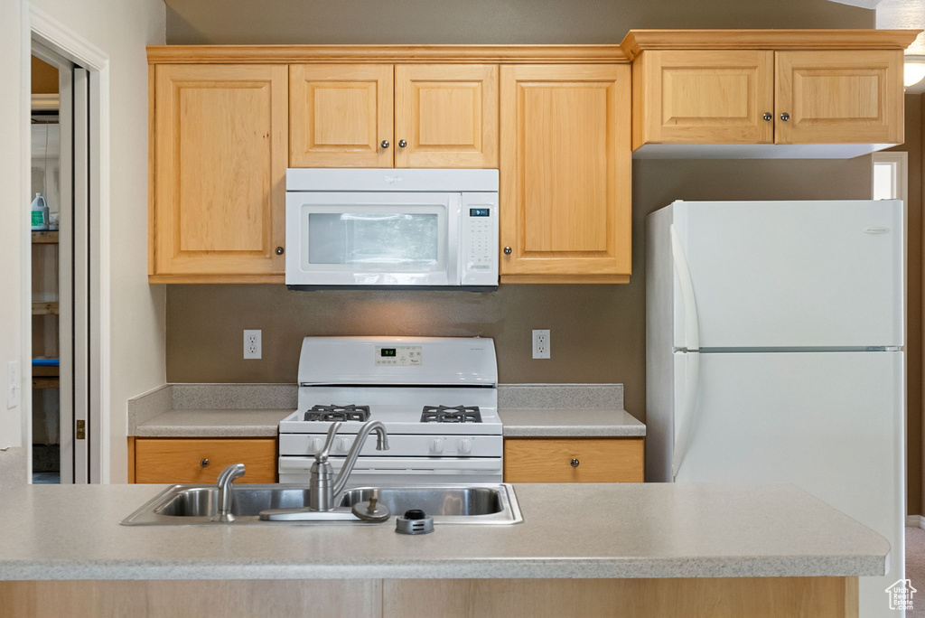 Kitchen featuring white appliances, light brown cabinets, and light countertops