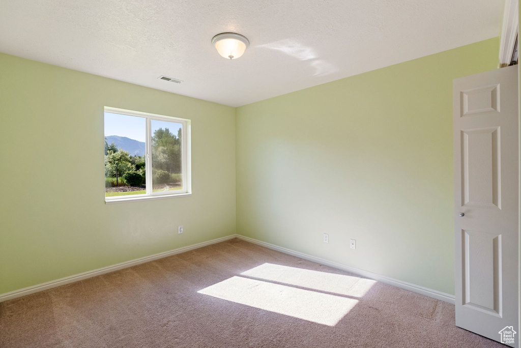 Carpeted spare room featuring baseboards and a mountain view