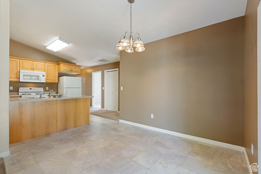 Kitchen featuring white appliances, vaulted ceiling, light countertops, a chandelier, and pendant lighting