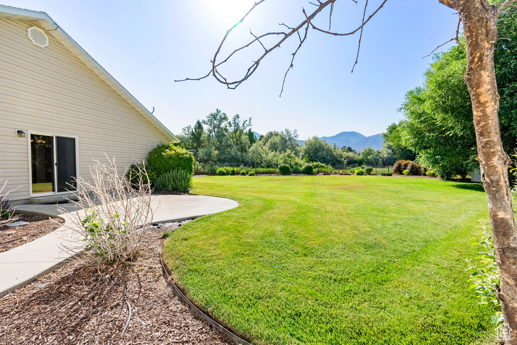 View of green lawn with a mountain view and a patio area