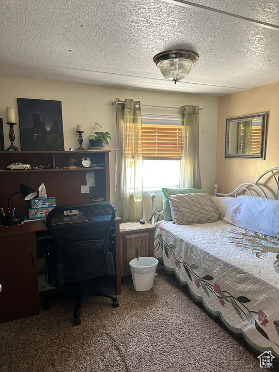 Bedroom featuring carpet flooring, an office area, and a textured ceiling