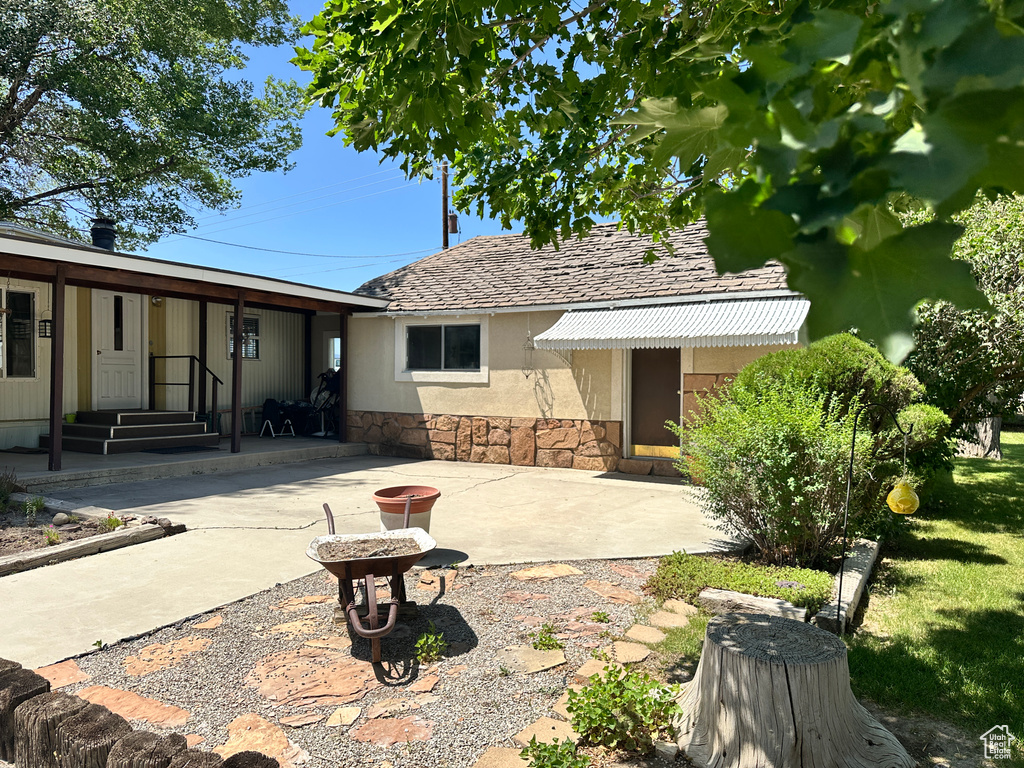 Back of house with stone siding, a patio area, and stucco siding
