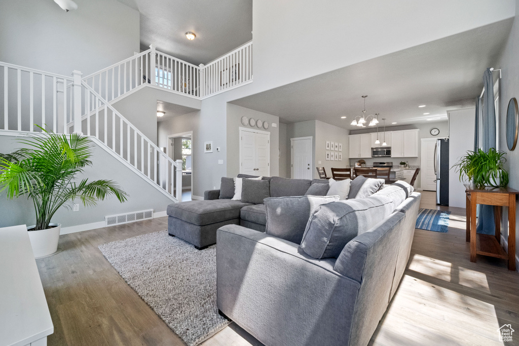Living area featuring a chandelier, stairs, wood finished floors, a high ceiling, and recessed lighting