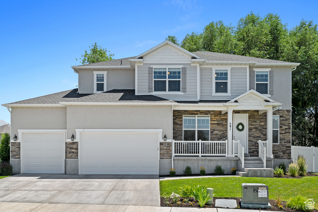 View of front facade featuring a porch, an attached garage, stone siding, and concrete driveway