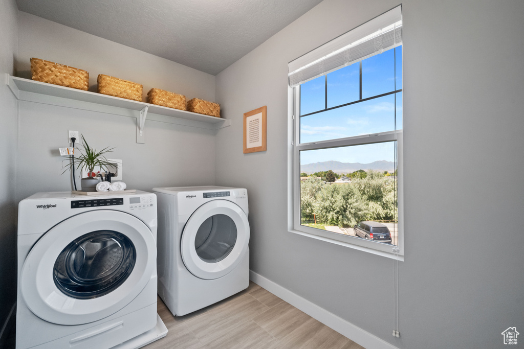 Washroom featuring washing machine and clothes dryer, plenty of natural light, and light wood-type flooring