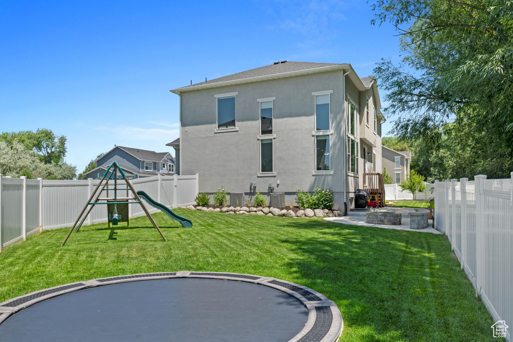 Rear view of property with a playground, stucco siding, and a fenced backyard