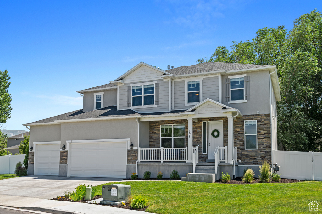 View of front of house with stone siding, an attached garage, concrete driveway, stucco siding, and covered porch