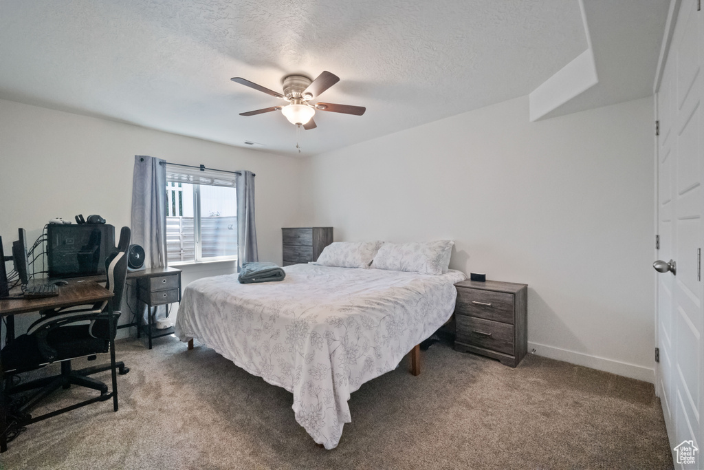 Bedroom with carpet, ceiling fan, a textured ceiling, and a desk